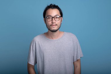 Genç adam portre mavi arka planda sakallı. Asya genç hippi gülümseyen, yarım vücut vurdu. Genç nesil yenilikçi kavram.