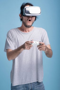 Genç adam Vr oyunu mavi arka planda çalmaya sakallı. Asya genç hipster giyen Vr kulaklık, yarım vücut vurdu sürpriz. Genç nesil yenilikçi gevşeme kavramı.