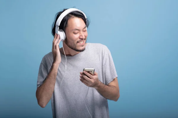 Ung Skäggig Man Lyssnar Musik Blå Bakgrund Mycket Koppla Asiatiska — Stockfoto