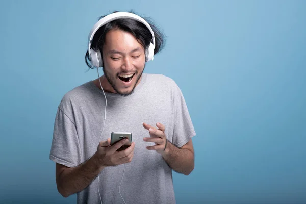 Joven Barbudo Hombre Buscando Lista Reproducción Teléfono Fondo Azul Feliz —  Fotos de Stock