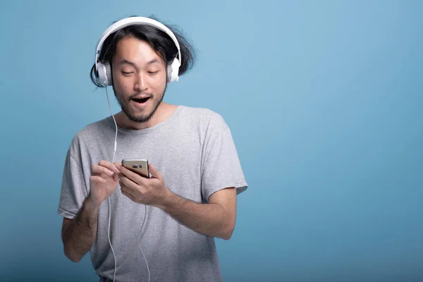 Young Bearded Man Browsing Playlist Phone Blue Background Happy Asian — Stock Photo, Image