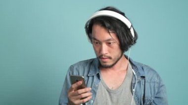 Genç erkek hippi müzik sakallı. Çalma listesi tarama sıkılmış Asya adam doğru bir şarkı bulmak ve onun müzik arka plan mavi tadını çıkar.