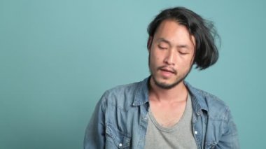 Harika bir haber bulmak için erkek hipster telefonuna cevap Genç sakallı. Onun cep telefonu ve aşırı mutlu o mavi arka plan ile iyi bir haber duydum gibi sıkılmış Asyalı adam. 