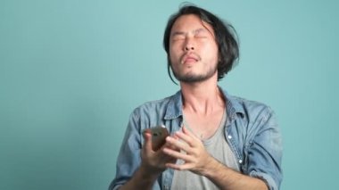 Genç erkek hipster mutlu büyük haber telefonundan sonra sakallı. O iyi haber--dan onun telefon mavi arka plan ile gördükten sonra Asya adam çok mutludur.