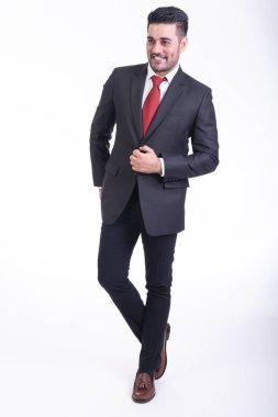 Beyaz arka planda izole iş adamı. Takım elbise portre yakışıklı genç Hintli işadamı, elleri cebinde görünüyor gülümse. Tam uzunlukta vurdu.