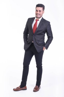 Beyaz arka planda izole iş adamı. Takım elbise portre yakışıklı genç Hintli işadamı, elleri cebinde görünüyor gülümse. Tam uzunlukta vurdu.