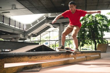 Kaykaycı eylem. Asyalı çocuk kentsel kaykay parkı hile yaparak köprünün altında. Doğal ışık ayarı.