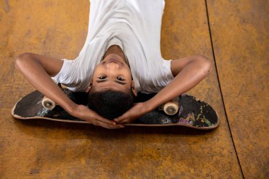 Kaykaycı portre. Kentsel kaykay parkı kirli rampa üzerinde döşeme köprünün altından gülümseyen Asyalı çocuk. Doğal ışık ayarı.