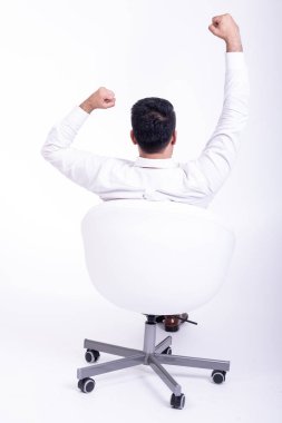 İş adamı izole beyaz sandalyede oturuyor. Yakışıklı genç Hintli işadamı sandalye kazanan poz. Tam uzunlukta geri vurdu.