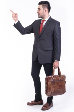 Beyaz arka planda izole iş adamı. Yakışıklı genç Hintli işadamı çanta portre ile takım elbiseli, noktası parmak görünüyor. Tam uzunlukta vurdu.