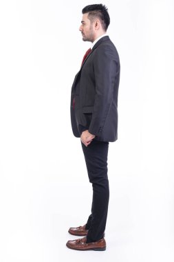 Beyaz arka planda izole iş adamı. Takım elbise portre yakışıklı genç Hintli işadamı, elleri ceplerinde görünüyor. Tam uzunlukta yan vurdu.