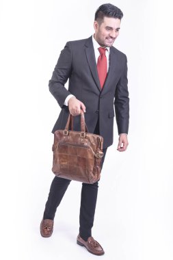 Beyaz arka planda izole iş adamı. Yakışıklı genç Hintli işadamı çanta portre ile takım elbiseli, kendine güvenen gülümseme görünüyor. Tam uzunlukta vurdu.