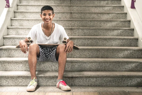 滑板肖像 微笑的亚洲男孩在城市滑板公园在桥下坐在楼梯上 自然光设置 — 图库照片
