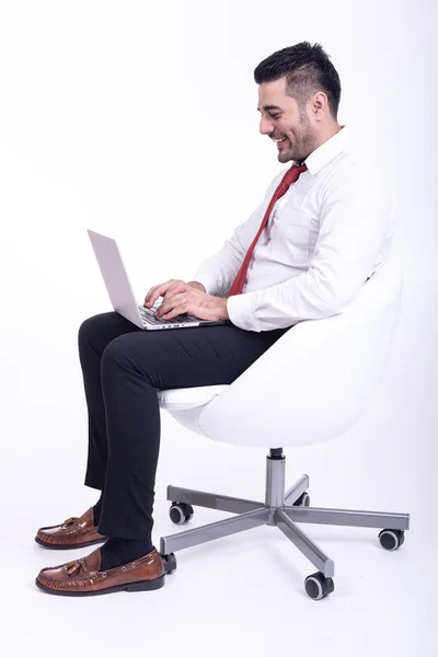 分離された白い椅子の上に座っての実業家 ハンサムな若いのインドのビジネスマンはノート パソコンの肖像画 自信を持って笑顔に見えるを使用して 全長側撮影 — ストック写真