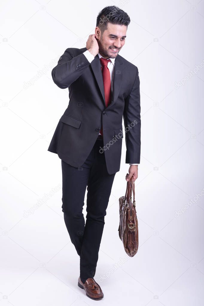 Businessman isolated in white background. Handsome young indian businessman in suit with bag portrait, thinking looks. Full length shot.