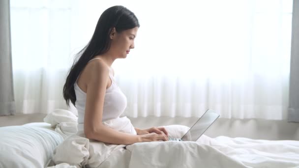 Attentive Young Asian Woman Sitting Bed Using Laptop — Stock Video