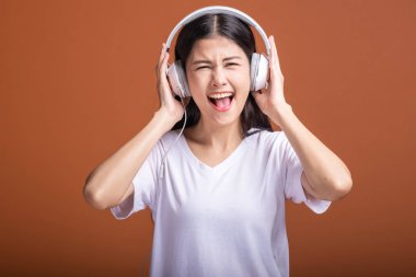Turuncu arka plan üzerinde izole kulaklık kullanan kadın. Genç Asyalı kadın baş telefon, heyecanlı ruh hali ile müzik dinlemek. Hipster yaşam tarzı kavramı,