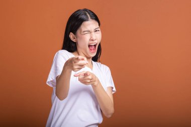 Turuncu arka plan üzerinde izole kadın kazanmak. Genç Asyalı hipster kadın beyaz t-shirt galibiyet sonrası, ilgili parmak işaret. Başarılı genç hipster kavramı.