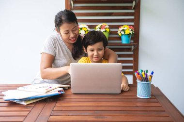 Çocuk ev ödevi. Teras evde ödev genç karışık yarış çocuk annesi ona rehberlik dizüstü bilgisayar kullanarak. Mutlu ruh hali. Geri okul kavramı.
