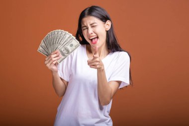 Turuncu arka planda izole nakit notlar tutan kadın. Genç Asyalı kadın kendinden emin kazanmak poz, beyaz t-shirt parmak işaret içinde. Genç zengin hipster kavramı.