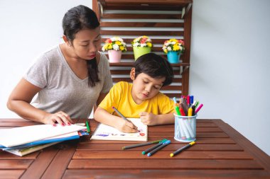 Çocuk ev ödevi. Genç karışık yarış çocuk ödev Teras evde annesiyle vermiyorsun. Çizim boyama. Odak ruh. Geri okul kavramı.