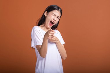 Turuncu arka plan üzerinde izole kadın kazanmak. Genç Asyalı hipster kadın beyaz t-shirt galibiyet sonrası, ilgili parmak işaret. Başarılı genç hipster kavramı.