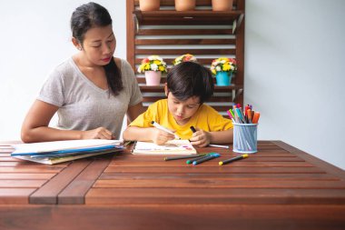 Çocuk ev ödevi. Genç karışık yarış çocuk ödev Teras evde annesiyle vermiyorsun. Çizim boyama. Odak ruh. Geri okul kavramı.