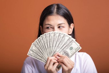 Turuncu arka planda izole nakit notlar tutan kadın. Çok kıskanç havada beyaz t-shirt doları not tutan Genç Asyalı kadın. Genç zengin hipster kavramı.