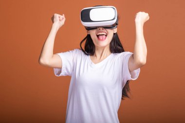Kadın giyiyor Vr kulaklık. Beyaz t-shirt Vr kafa dişli, büyük kazanç poz ile Genç Asyalı kadın. Yeni eğlence kavramının.
