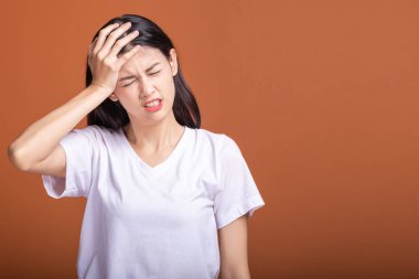Turuncu arka plana düşünce kadın. Genç Asyalı hipster kadın beyaz t-shirt ile büyük headarch poz, kafasına ver. Genç kadın hipster kavramı.