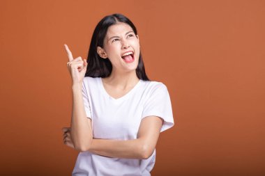 Turuncu arka plana düşünce kadın. Genç Asyalı hipster kadında saç çekerek beyaz t-shirt fikir atılım poza sahip. Genç kadın hipster kavramı.