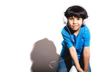 Genç çocuk sert ışık ile beyaz arka plan müzik portre dinlerken. Mavi gömlek ve jean karışık yarış çocuk. Dans.