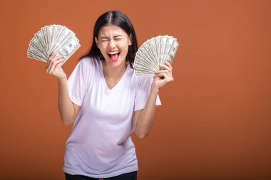 Turuncu arka planda izole nakit notlar tutan kadın. Çok mutlu çığlık, beyaz t-shirt doları not tutan Genç Asyalı kadın. Genç zengin hipster kavramı.