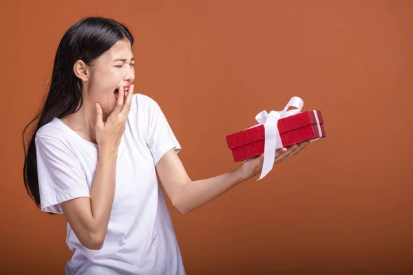 Young hipster girl got a gift. Asian woman in white t-shirt holding a red present gift box, very excited mood. Holiday gift concept.