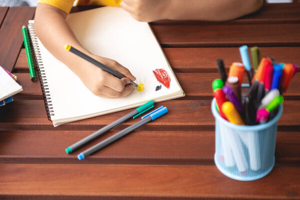 Домашнее задание. Молодой смешанный расовый мальчик делает домашнее задание на террасе дома. Рисование цвета. Сосредоточься. Снова в школу
.