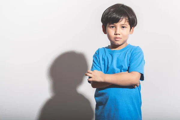 Young boy portrait in white background with hard light. Mixed race boy in blue shirt and jean.