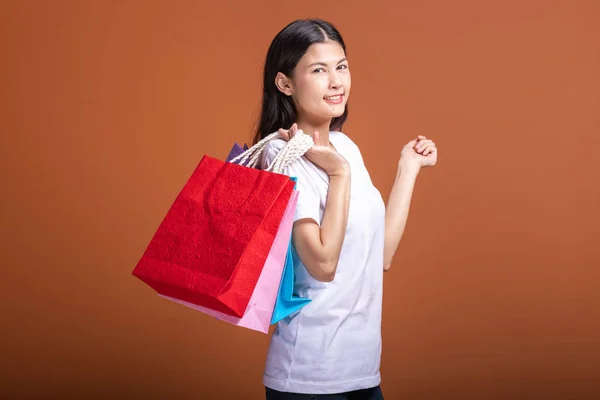 オレンジ色の背景で分離された買い物袋を持った女性 シャツ 幸せな気分で若いアジア女性 ショッピング概念 — ストック写真