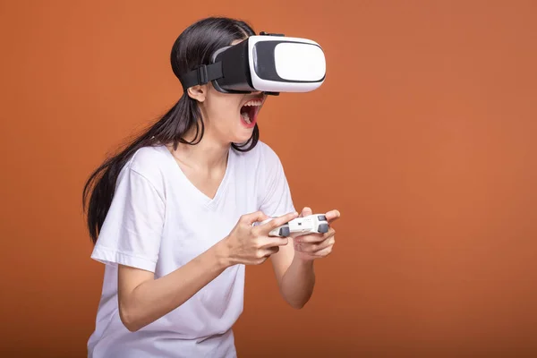 Woman wearing VR headset. Young Asian woman in white t-shirt with VR head gear, very excited pose. New entertainment concept.