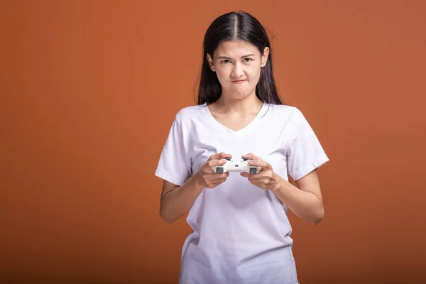 オレンジ色の背景に分離する女性のゲーマー コンソール ゲームのジョイスティックを持つ若いアジア流行に敏感な女性は ムードを混乱させます 流行に敏感な楽しい時間概念 — ストック写真