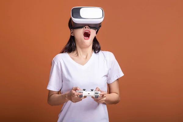 Woman wearing VR headset. Young Asian woman in white t-shirt with VR head gear, extremely shocking pose. New entertainment concept.