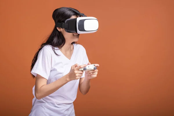 Woman wearing VR headset. Young Asian woman in white t-shirt with VR head gear, looking at camera. New entertainment concept.