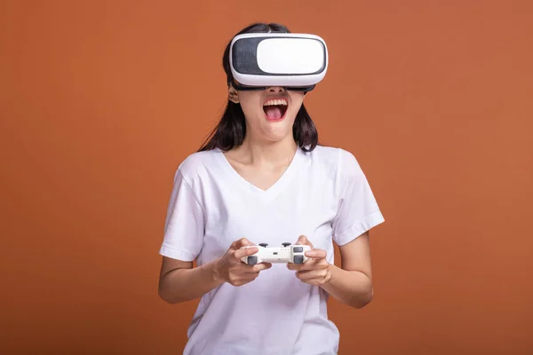Woman wearing VR headset. Young Asian woman in white t-shirt with VR head gear, shocking pose. New entertainment concept.