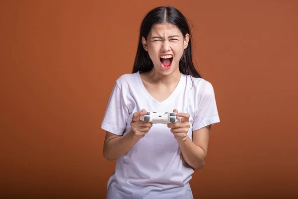 オレンジ色の背景に分離する女性のゲーマー 若いアジア流行に敏感な女性 コンソール ゲームのジョイスティックを保持しているエキサイティングな気分 流行に敏感な楽しい時間概念 — ストック写真