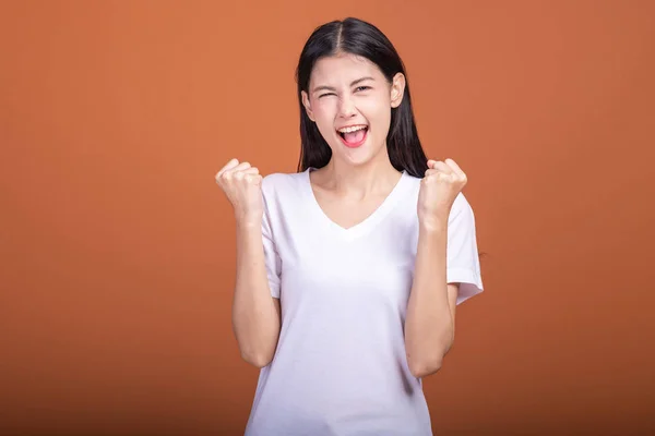 在橙色背景下被孤立的女人 年轻的亚洲时髦女人穿着白 T恤衫 用大赢的尖叫姿势 两手举起 成功的年轻时髦的概念 — 图库照片