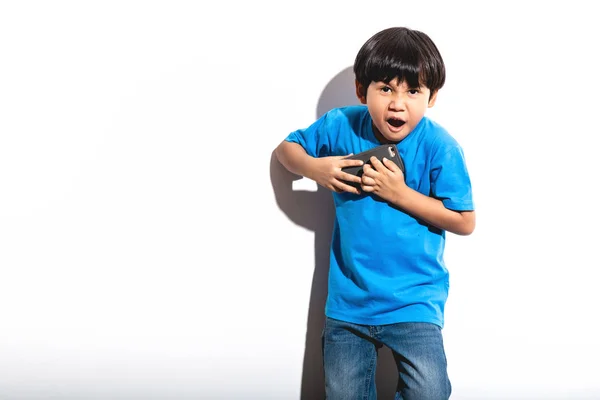 小男孩玩手机游戏肖像白色背景与硬光 穿着蓝色衬衣和琴的混血男孩 愤怒的心情 — 图库照片