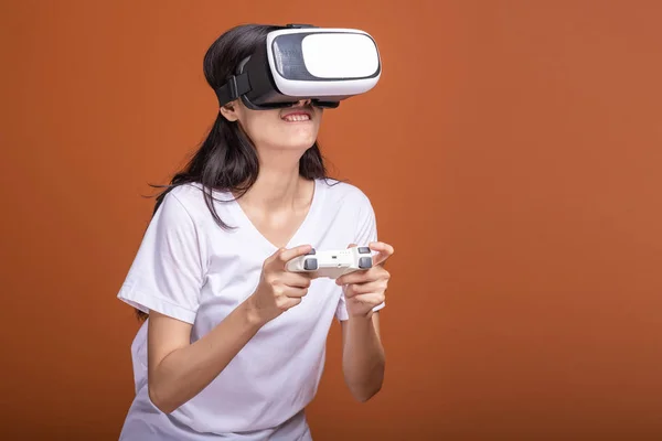 Woman wearing VR headset. Young Asian woman in white t-shirt with VR head gear, shocking pose. New entertainment concept.
