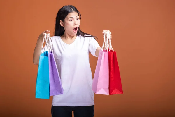 妇女拿着购物袋孤立的橙色背景 年轻的亚洲女人穿着白色 震撼心情 购物理念 — 图库照片