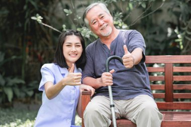 Hasta ile birlikte başparmak bankta oturan ile hemşire. Asyalı yaşlı adam ve birlikte konuşurken oturan bir genç bayan. Çok mutlu ruh hali.