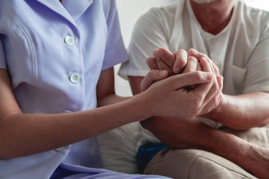 El rahatlatıcı. Genç tutan yaşlı adamın elini hemşire. Üst düzey bakım, bakım alıcı ve üst düzey emeklilik ev hizmet anlayışı. Atış kapatın.