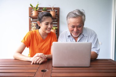 Kızı babası balkonda bilgisayar becerilerinin öğretimi. Asya adam beyaz sakalı ve dizüstü bilgisayar kullanarak Balkonda oturan bir genç bayan. Üst düzey yaşam tarzı Aile kavramı.
